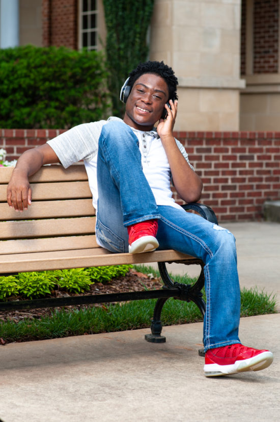 Young man sitting on bench holding headphones